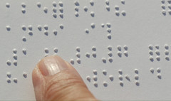 Closeup of a finger reading Braille on paper